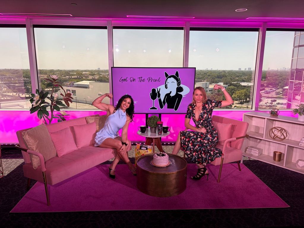 Alexia Tuttle on a podcast set with a host, both flexing, in front of a Gal On The Prowl screen.