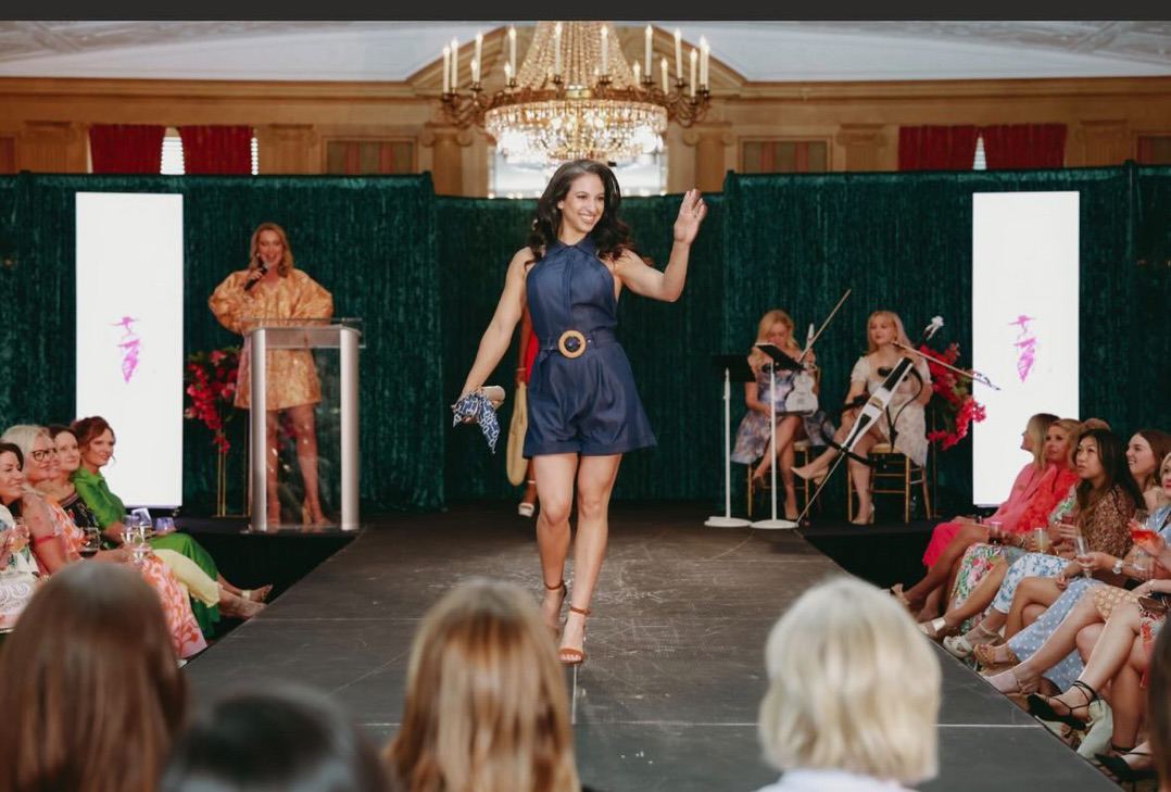 Alexia Tuttle walking a runway at a fashion show in a ballroom at the Fort Worth Club.
